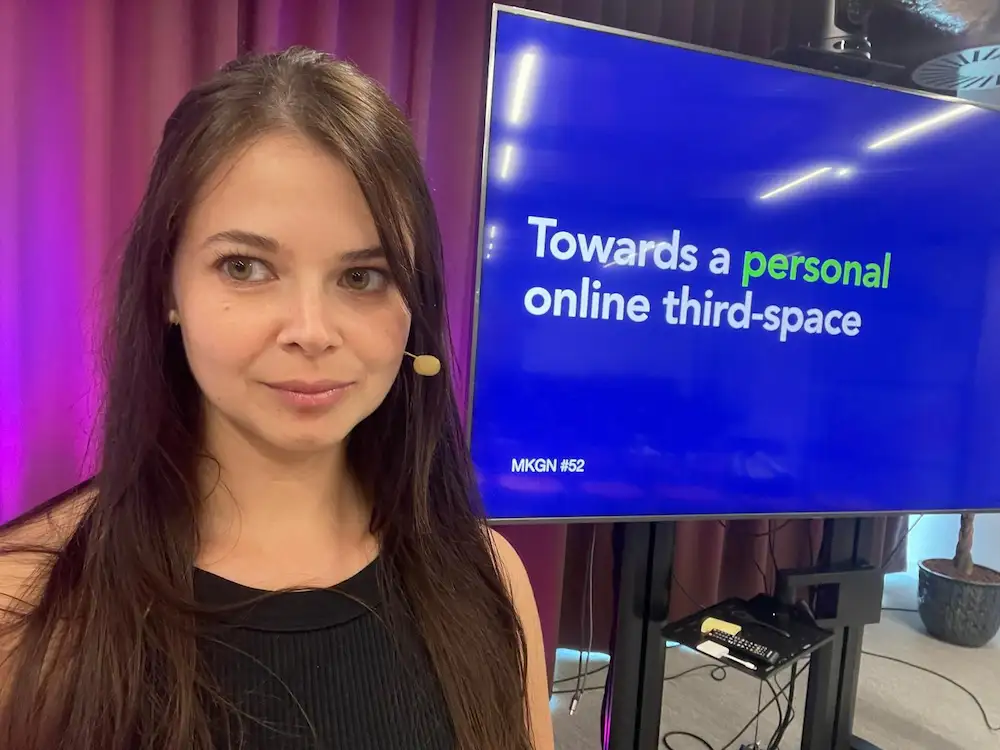 Selfie wearing a microphone in front of a screen with the title of my talk.