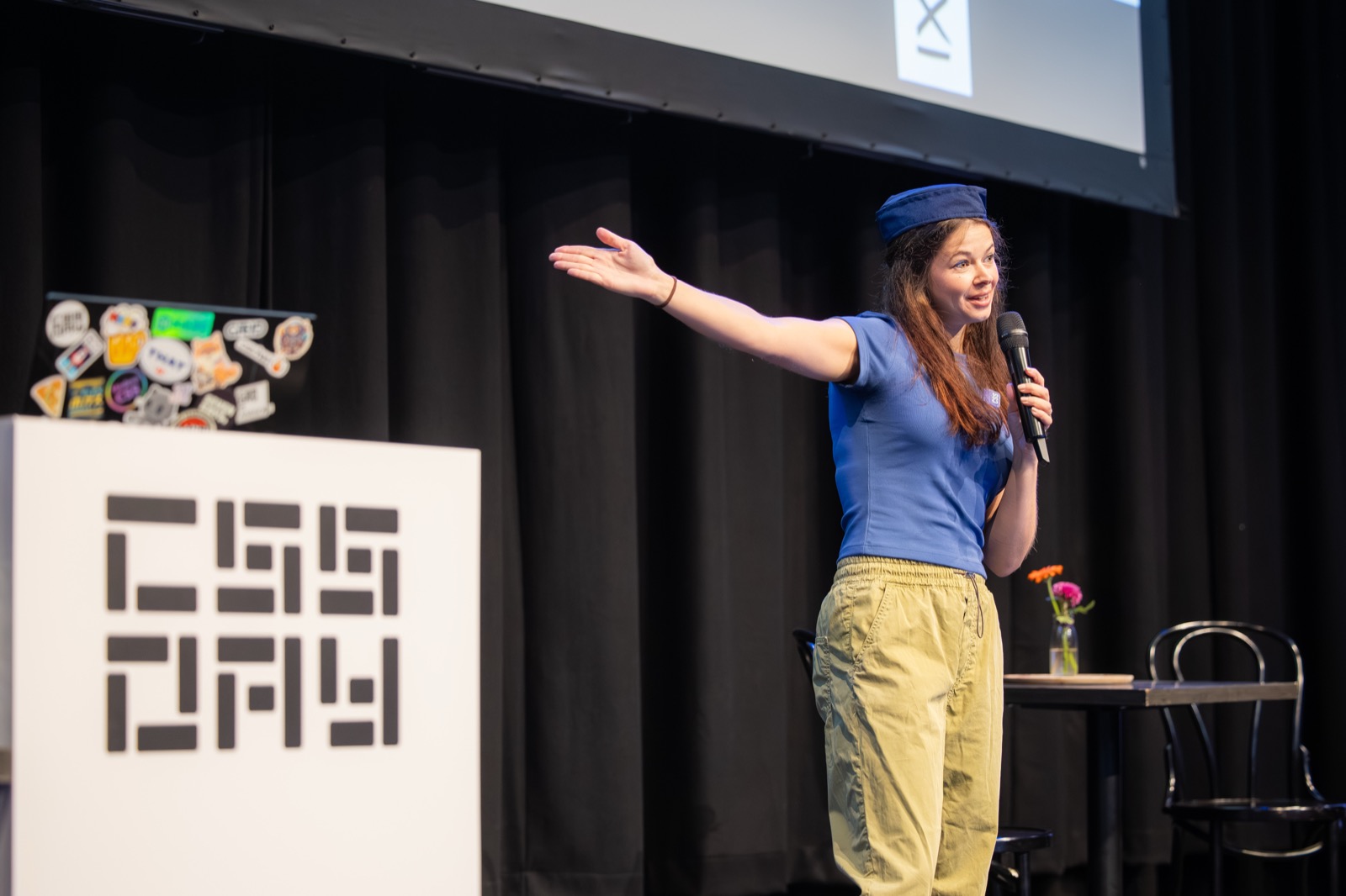 Me on the stage of CSS Day wearing an air host hat and pointing to the loos.