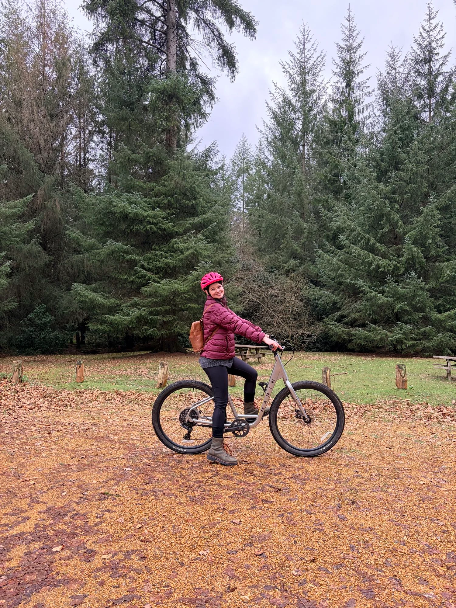 Me on a bicycle in front of tall trees.